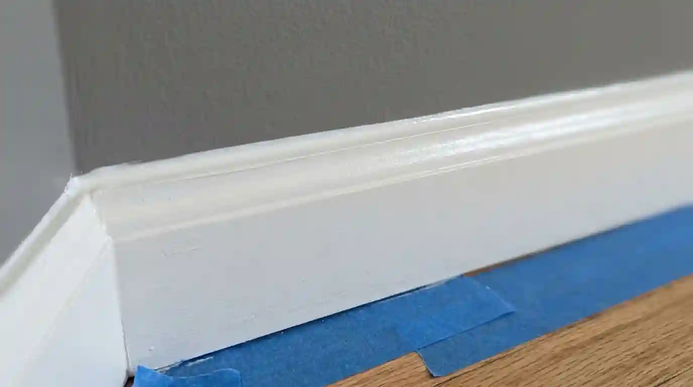 Fresh caulk line between baseboard and gray wall